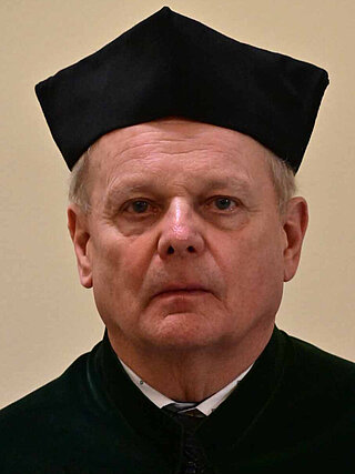 Oficjalna fotografia portretowa dr. hab. inż. Zbigniewa Fąfary, profesora uczelni, Prodziekana ds. Studenckich Wydziału Wiertnictwa, Nafty i Gazu AGH. Sylwetka ujęta od pasa w górę, w czarnej todze akademickiej z biretem, na jednolitym jasnym tle studyjnym.