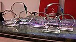 Nagrody Przewidziane dla zwycięzców Konferencji East meet West- szklane przezroczyste trofea stojące na zielonym marmurowym blacie